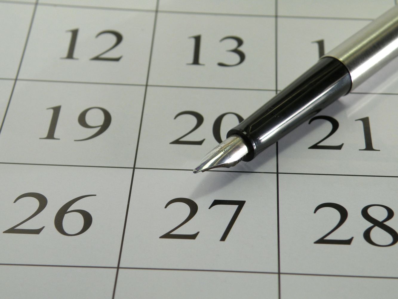Fountain pen resting on calendar date 27.