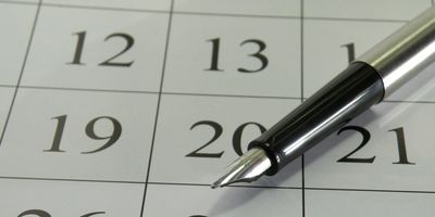 Close-up of a pen on a calendar showing dates 19, 20, and 21.