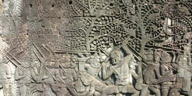 Ancient stone carving depicting a battle scene with warriors and trees.