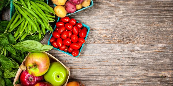 Fresh vegetables and fruits arranged on a wooden surface.