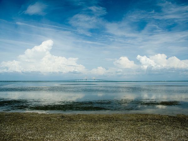Bridge stretching across calm water under a partly cloudy sky.
