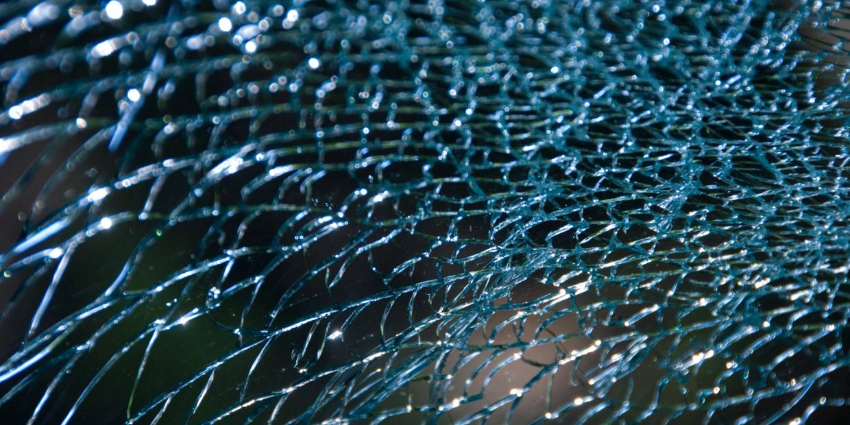 Close-up of shattered glass with light reflections.