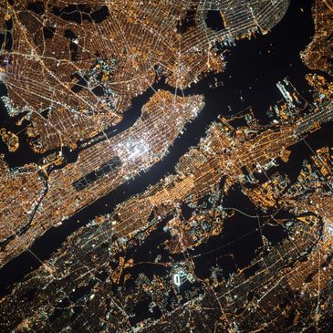 Nighttime aerial view of a brightly lit urban cityscape with waterways.