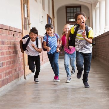 Four children running down a school hallway