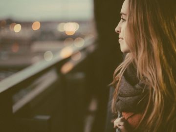 Mujer pensativa mirando al horizonte al atardecer.