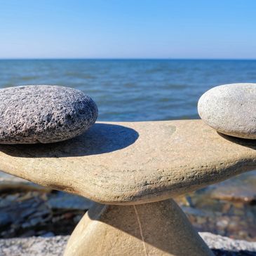 two rocks on top of a stone by the ocean