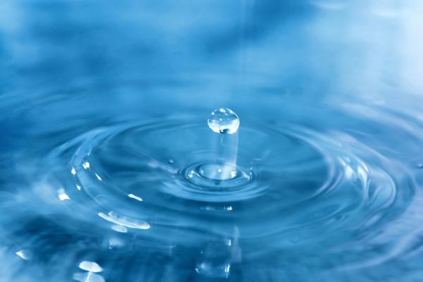 A water droplet splashing into a calm blue surface.