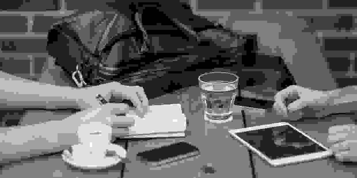 Image of hands resting on each side of table. It represents a marketing meeting or marketing consult