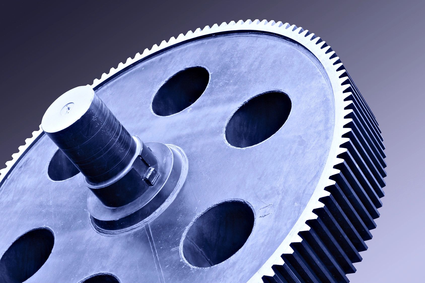 Close-up of a metallic gear with teeth and holes.