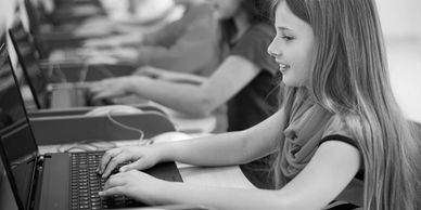 Children using laptops in a classroom setting.