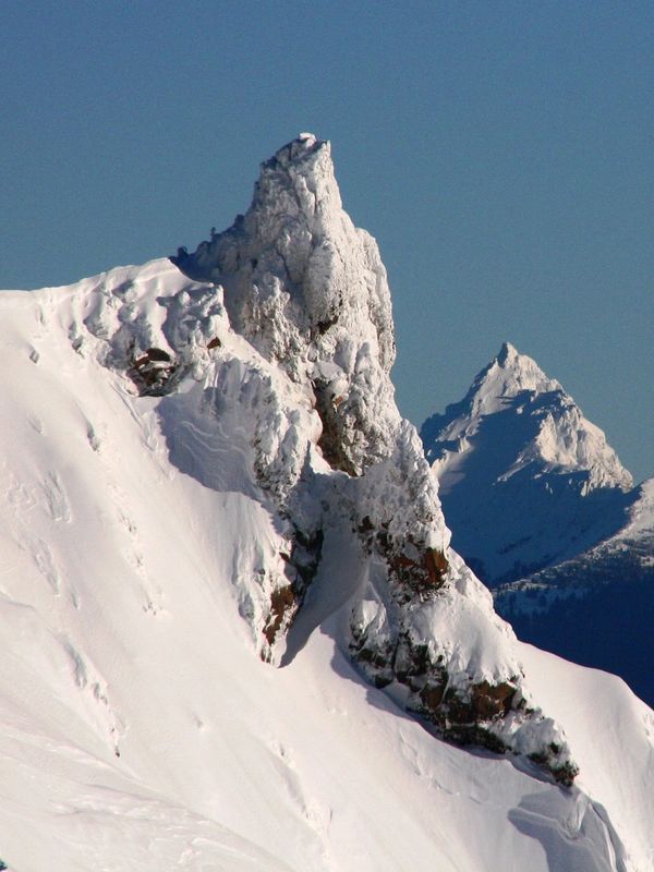 Snow-covered jagged mountain peaks under a clear blue sky.