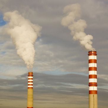 Two industrial smokestacks emitting smoke