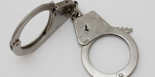 A pair of metallic handcuffs on a plain background.