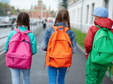 Three children walking with backpacks on