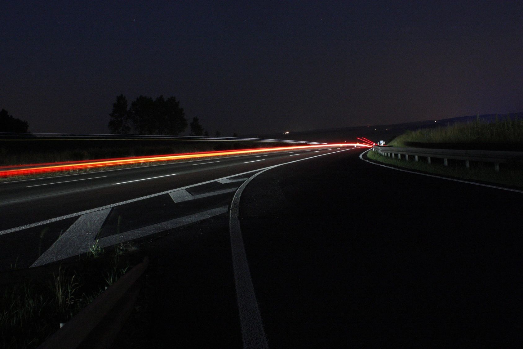 Light trails from vehicles on a dark highway at night.