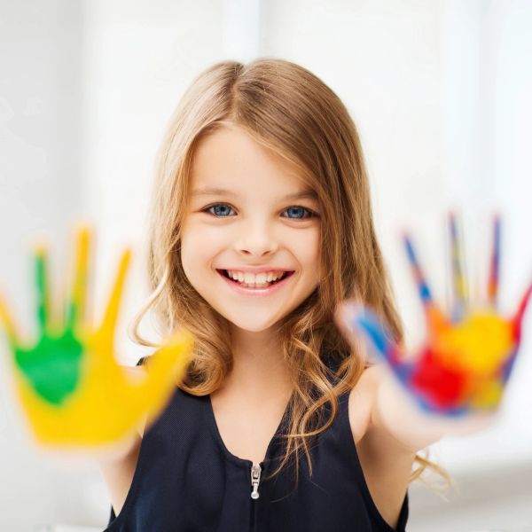 Smiling girl showing colorful painted hands.