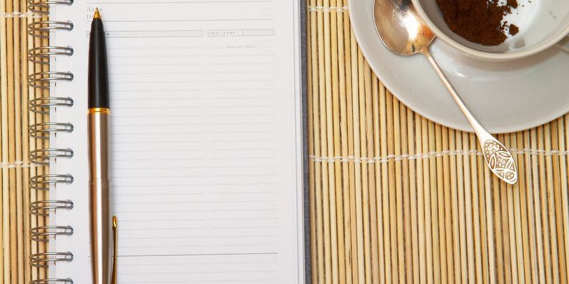Notepad and pen, coffee cup on table