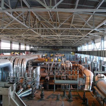 Interior de una planta industrial con tuberías y maquinaria.