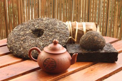 Traditional Chinese tea set with pressed tea cakes and a clay teapot on wooden table.