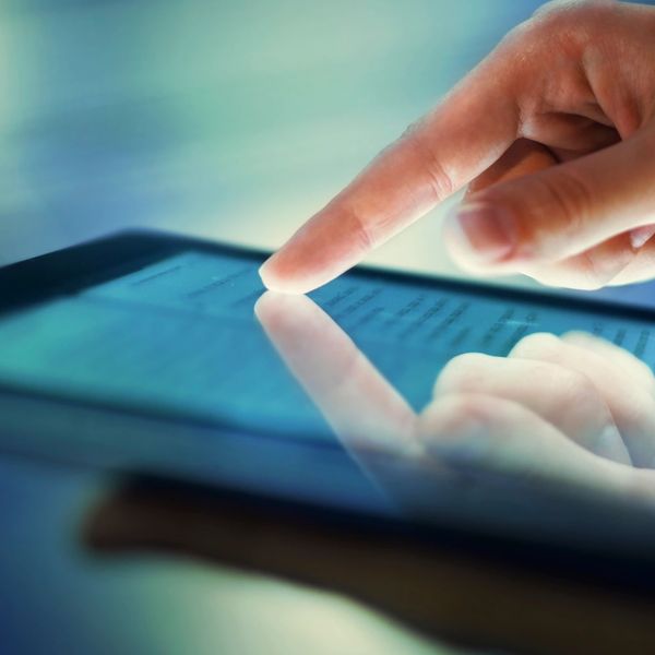 Finger touching and interacting with a tablet screen.
