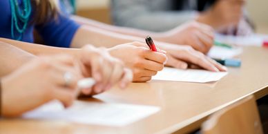 students writing with paper and pen