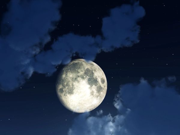 Bright full moon illuminating a cloudy night sky.
