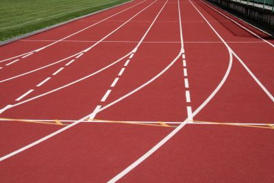 Empty red running track lanes with white markings and a finish line tape.