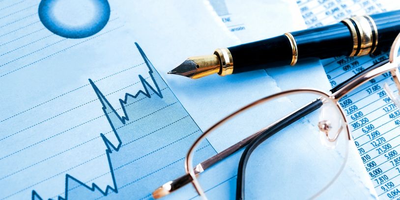 Pen and glasses on financial documents with charts.