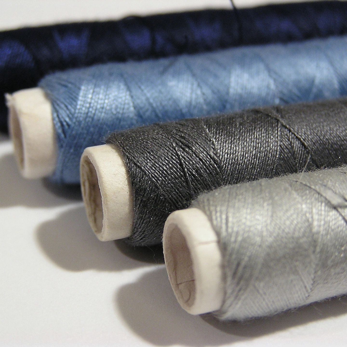 Close-up of spools of thread in various shades of blue and gray.