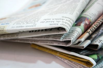 A stack of folded newspapers on a white surface.