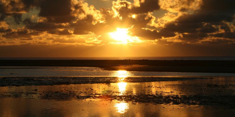 Hopeful sunlight peeks through dark depressing clouds over water. Teen counseling for depression.