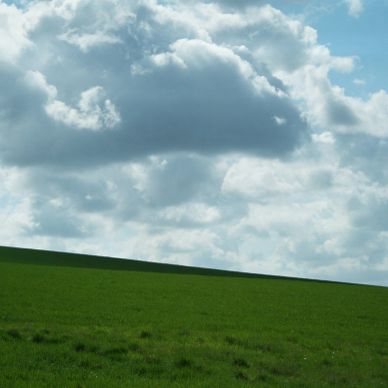 Green grassy hill under a partly cloudy blue sky.