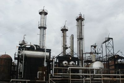 Industrial refinery facility with tall distillation columns under a cloudy sky.