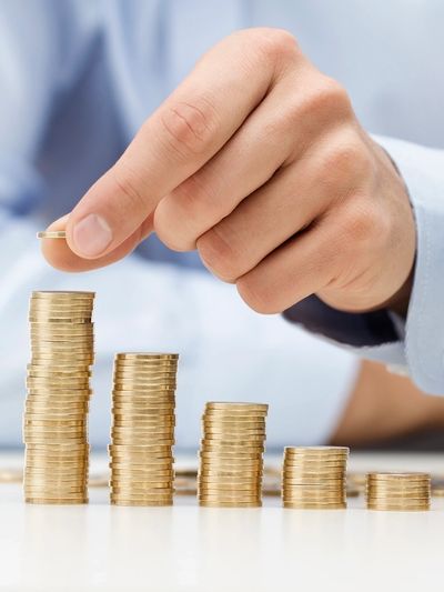 Hand stacking coins in ascending order on a table.