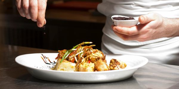 Chef seasoning gourmet dish with precision.