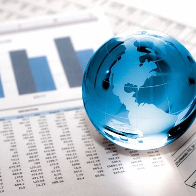 Blue glass globe on financial documents with charts.