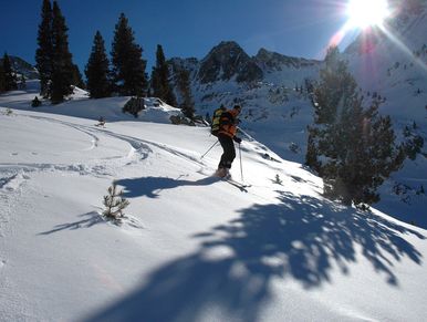 Backcountry downhill skier skiing on a blue sky sunny day.