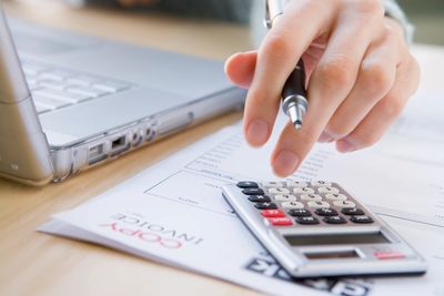 person working with calculator and laptop working