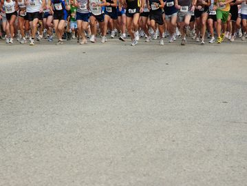 Runners starting a road race, showing their legs and feet in motion.