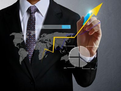 Businessman drawing a rising yellow arrow with charts and world map background.