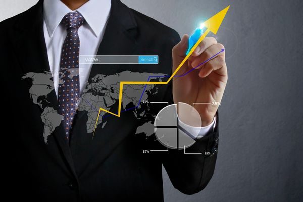 Businessman drawing a rising arrow and charts.