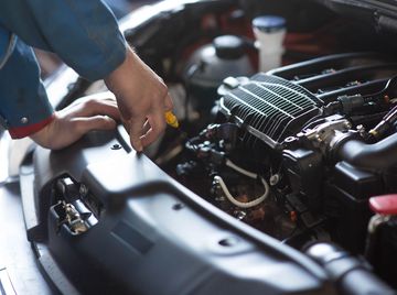 A person checking the oil level in a car engine.