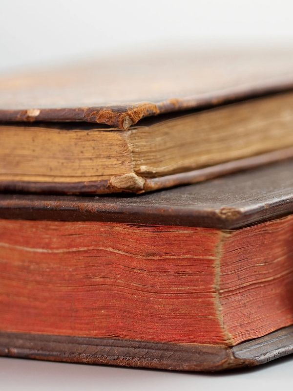 Close-up of two old, worn books stacked.