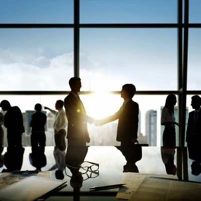 Business professionals shaking hands in a modern office with city view.