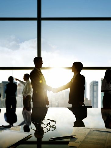 Businesspeople shaking hands in an office with city view.