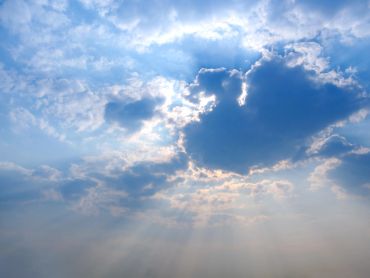 Sun rays shining through partly cloudy sky.