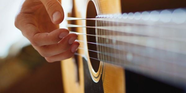 Hand strumming acoustic guitar strings