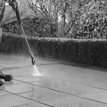 Person pressure washing outdoor tiles to clean them.