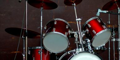 A red drum set with cymbals and microphones on a dark background.
