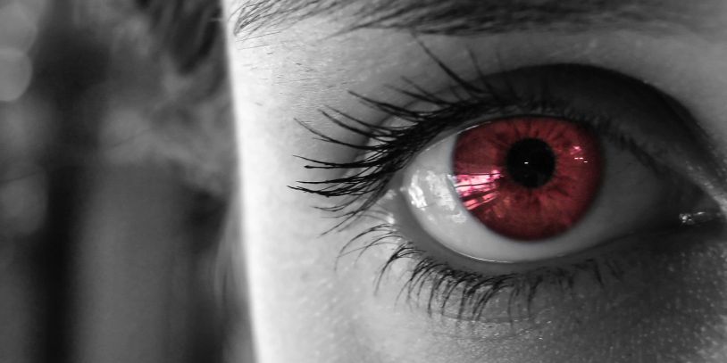 Close-up of an eye with a striking red iris and black-and-white surroundings.